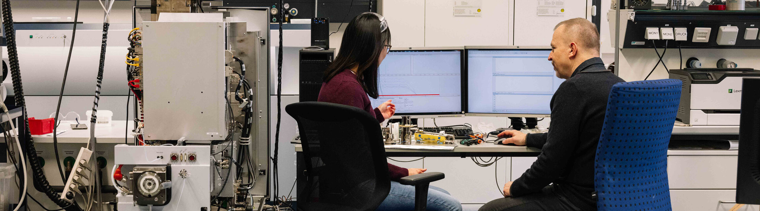 A woman and a man in a laboratory in front of a computer.